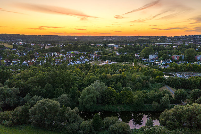 Luftbild von Schwerte bei Sonnenuntergang mit Wohngebieten, Bäumen und der Ruhr im Vordergrund.