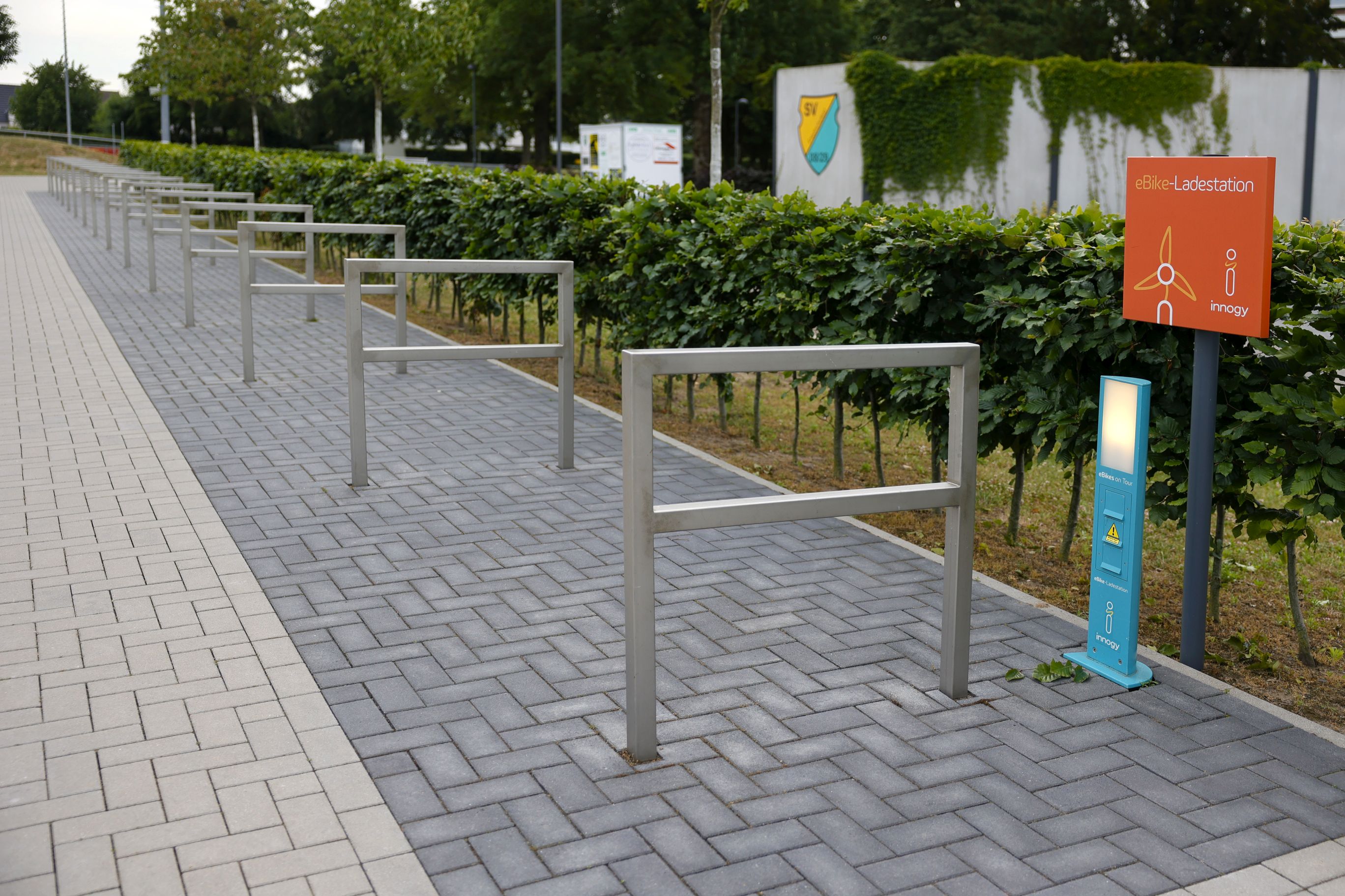 Ladestation für E-Bikes im Vordergrund und Fahrradständer dahinter